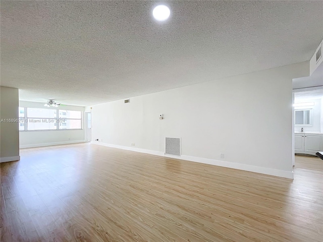 unfurnished room with ceiling fan, light hardwood / wood-style floors, and a textured ceiling