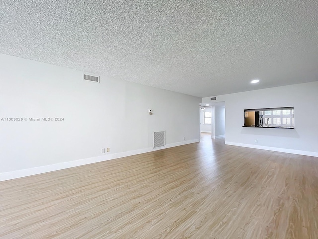 unfurnished living room featuring a textured ceiling and light hardwood / wood-style floors