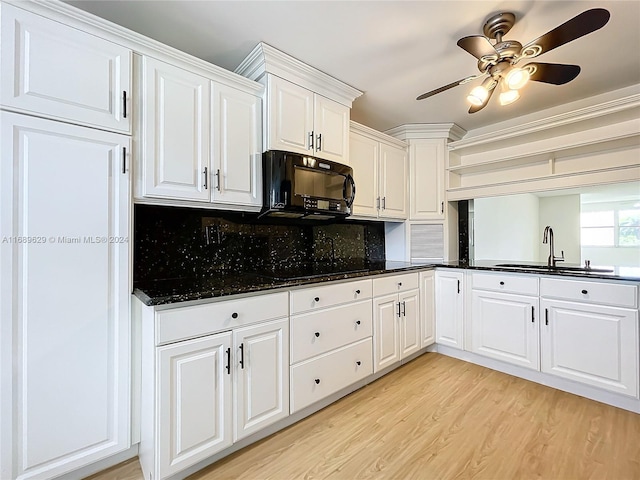 kitchen with backsplash, sink, black appliances, light hardwood / wood-style flooring, and white cabinets