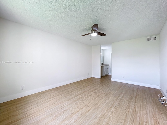 empty room featuring ceiling fan, a textured ceiling, and light hardwood / wood-style flooring