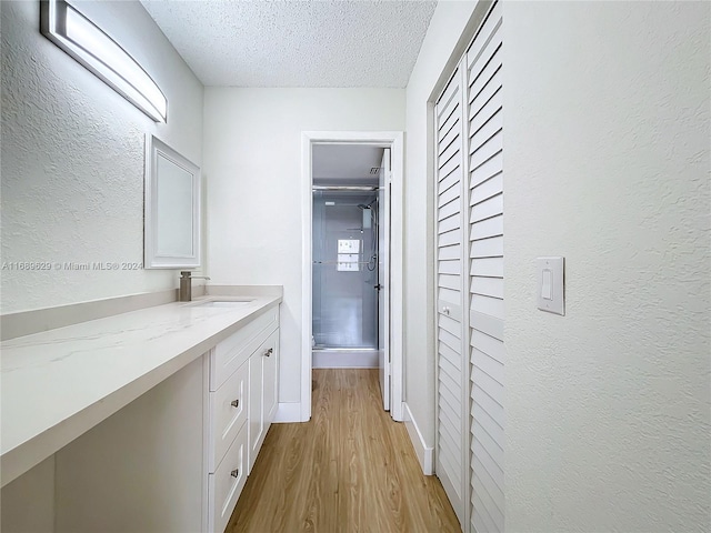 hall featuring sink, a textured ceiling, and light hardwood / wood-style flooring