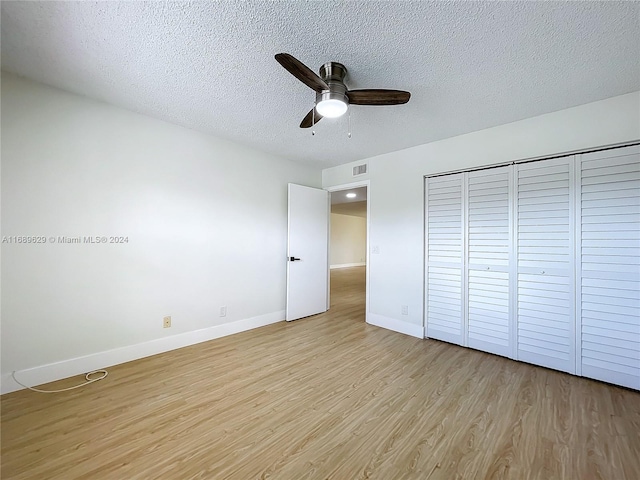 unfurnished bedroom with ceiling fan, a closet, a textured ceiling, and light wood-type flooring