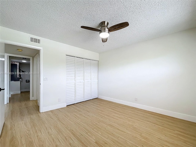 unfurnished bedroom with ceiling fan, a closet, light hardwood / wood-style floors, and a textured ceiling