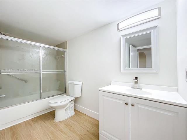 full bathroom with hardwood / wood-style floors, vanity, enclosed tub / shower combo, and toilet