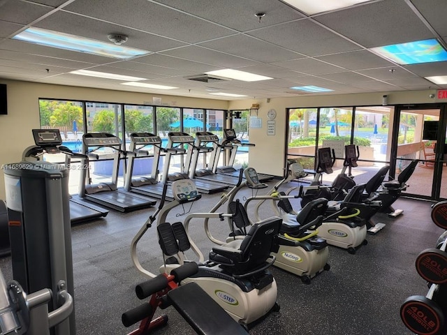 gym with a paneled ceiling and a healthy amount of sunlight