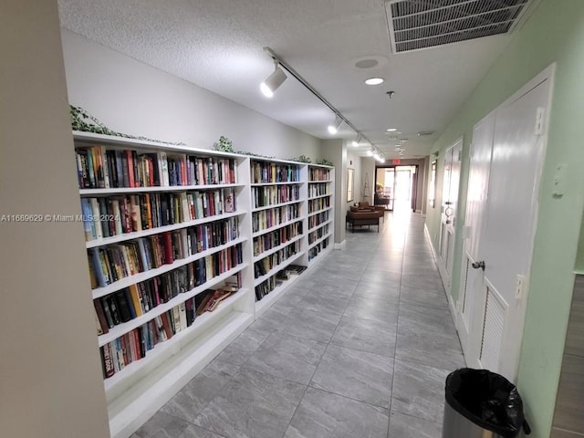 hallway with a textured ceiling and track lighting