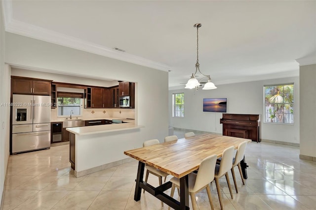 dining room featuring light tile patterned flooring, a chandelier, crown molding, and plenty of natural light