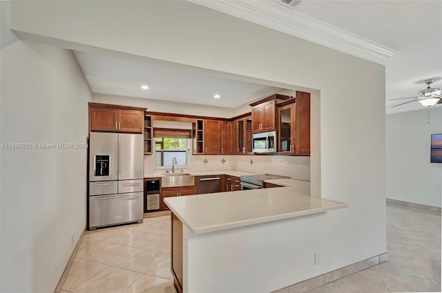 kitchen featuring tasteful backsplash, appliances with stainless steel finishes, light tile patterned floors, sink, and kitchen peninsula