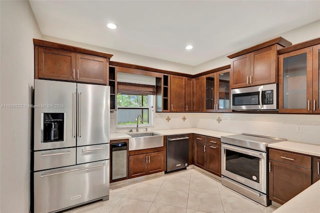 kitchen with decorative backsplash, sink, light tile patterned floors, and stainless steel appliances