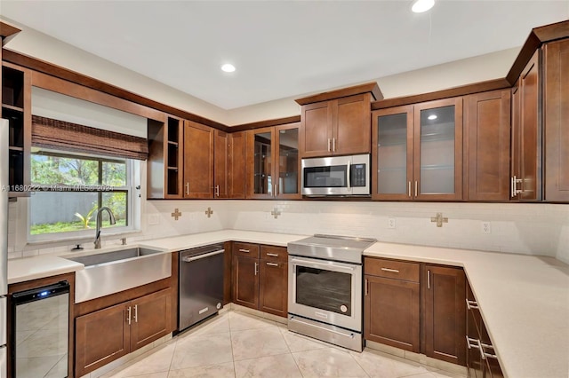 kitchen featuring decorative backsplash, stainless steel appliances, sink, and light tile patterned floors