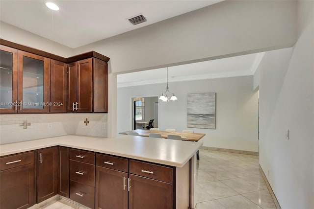 kitchen with kitchen peninsula, an inviting chandelier, hanging light fixtures, dark brown cabinets, and decorative backsplash