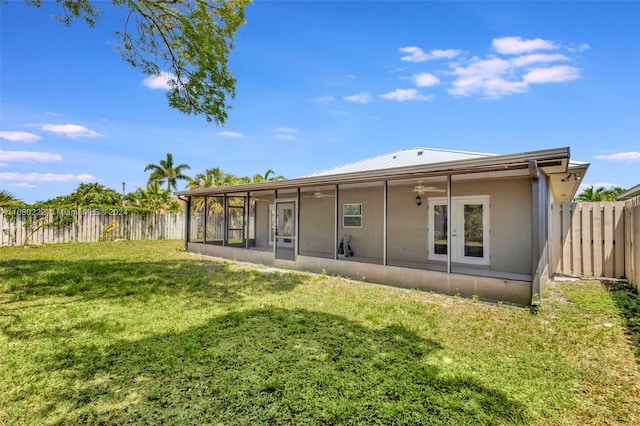 back of property with ceiling fan, a sunroom, and a yard