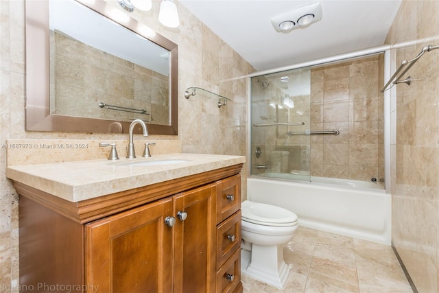 full bathroom with tasteful backsplash, shower / bath combination with glass door, vanity, toilet, and tile walls