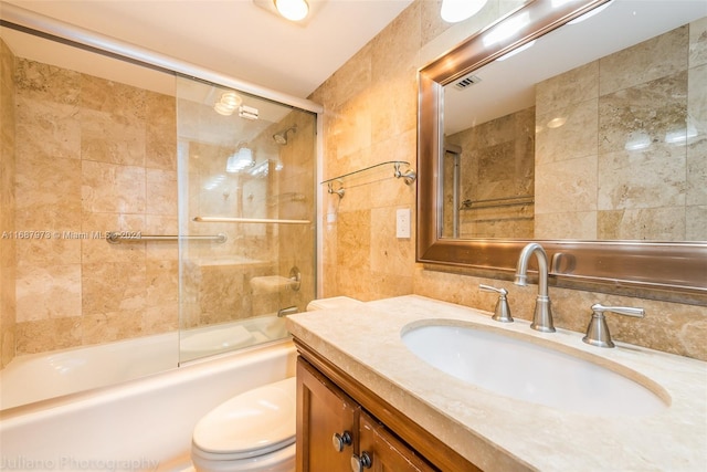 full bathroom featuring tile walls, shower / bath combination with glass door, toilet, and vanity