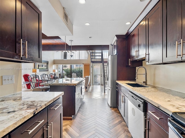 kitchen featuring stainless steel appliances, sink, light stone counters, hanging light fixtures, and light parquet floors