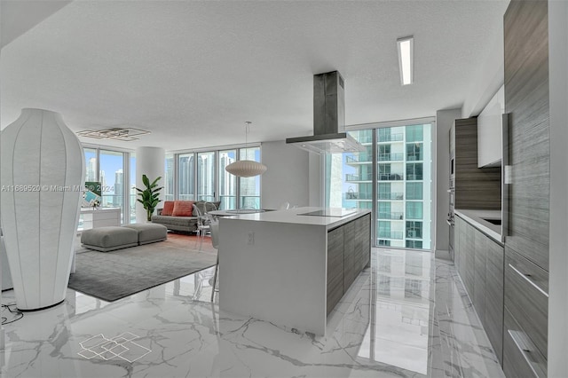 kitchen featuring island exhaust hood, a textured ceiling, floor to ceiling windows, and a center island