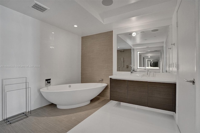 bathroom with independent shower and bath, tile patterned flooring, vanity, and tile walls