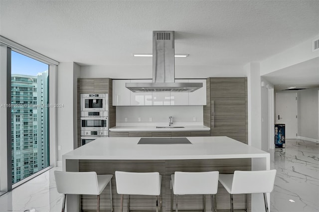 kitchen featuring black electric stovetop, a center island, white cabinets, a textured ceiling, and ventilation hood