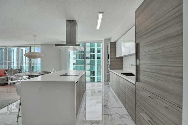 kitchen with island range hood, white cabinetry, a textured ceiling, decorative light fixtures, and a spacious island