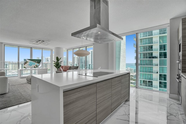 kitchen featuring expansive windows, a water view, black electric cooktop, island range hood, and a textured ceiling