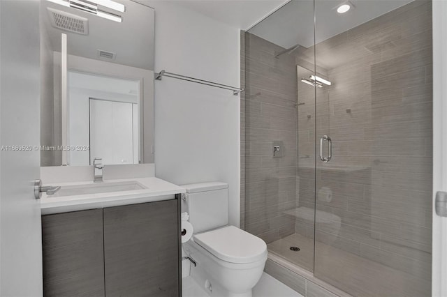 bathroom with toilet, vanity, and a shower with door