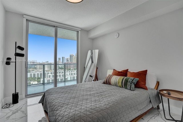 bedroom featuring access to exterior, expansive windows, and a textured ceiling