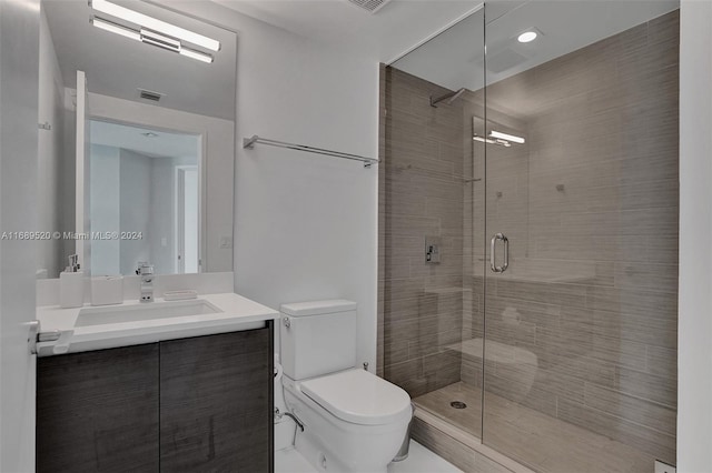 bathroom with vanity, toilet, and a shower with door