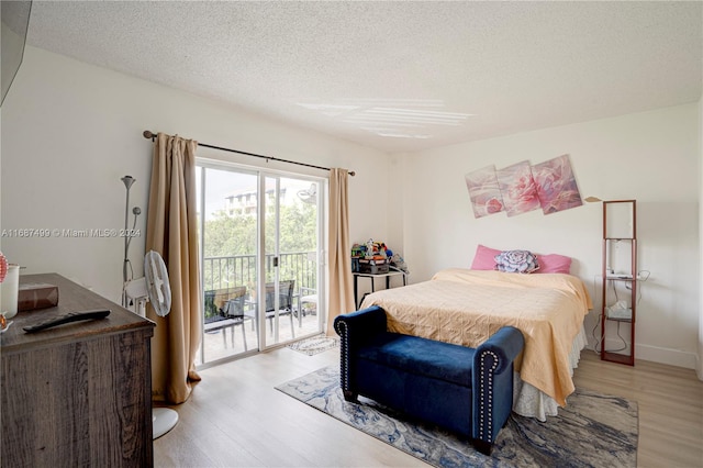 bedroom with a textured ceiling, access to outside, and light hardwood / wood-style floors