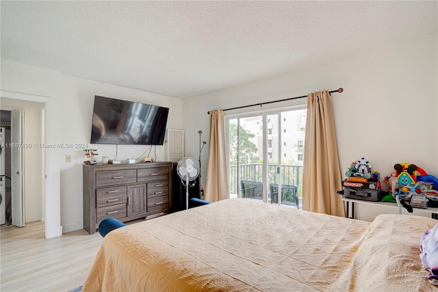 bedroom featuring access to exterior, light wood-type flooring, and a textured ceiling