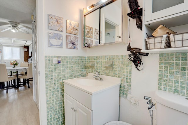 bathroom with vanity, ceiling fan, toilet, tile walls, and wood-type flooring