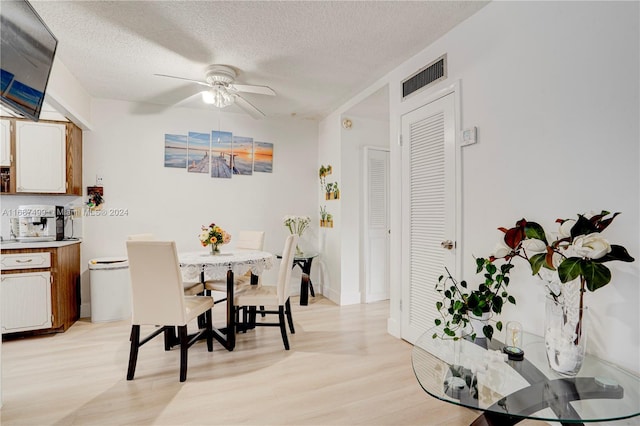 dining area with ceiling fan, light hardwood / wood-style floors, and a textured ceiling