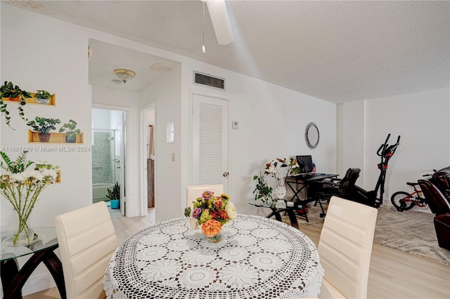 dining area featuring ceiling fan, light hardwood / wood-style flooring, and a textured ceiling