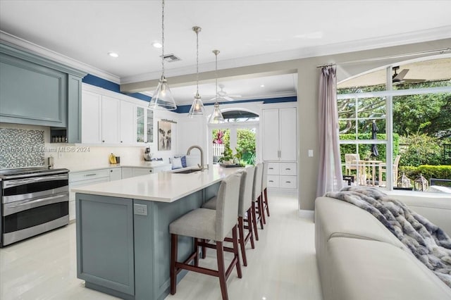 kitchen featuring backsplash, a center island with sink, hanging light fixtures, sink, and stainless steel stove