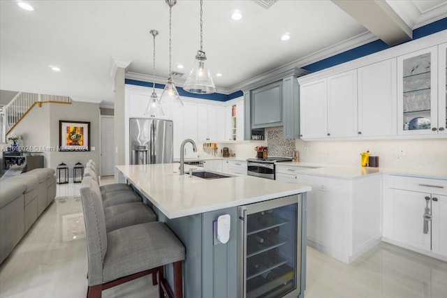 kitchen with a kitchen breakfast bar, sink, an island with sink, stainless steel appliances, and beverage cooler