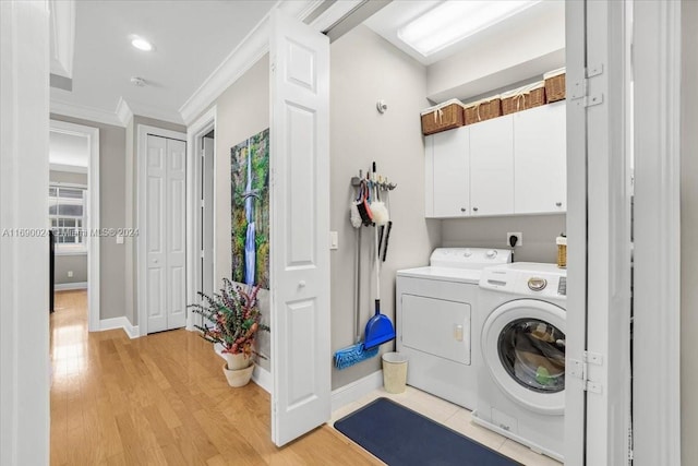 clothes washing area featuring cabinets, ornamental molding, light hardwood / wood-style floors, and independent washer and dryer