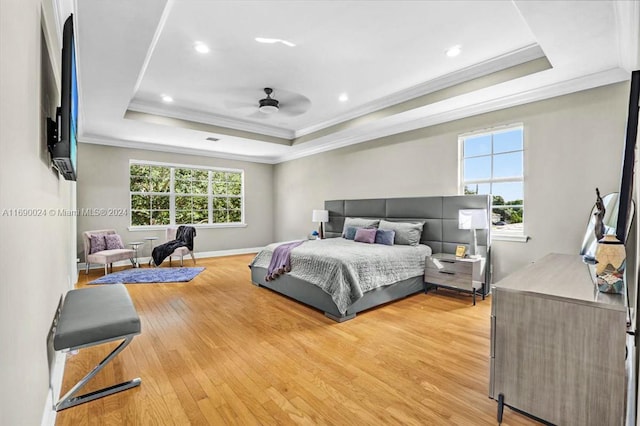 bedroom with ceiling fan, crown molding, a tray ceiling, and light hardwood / wood-style flooring