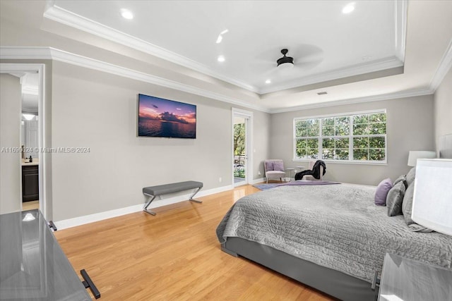 bedroom with a tray ceiling, ceiling fan, wood-type flooring, and ornamental molding