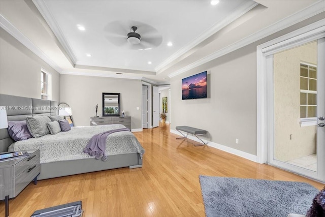 bedroom with ceiling fan, a raised ceiling, crown molding, and light hardwood / wood-style flooring