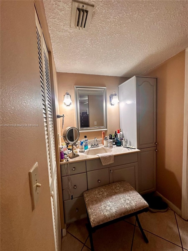 bathroom with vanity, a textured ceiling, and tile patterned floors