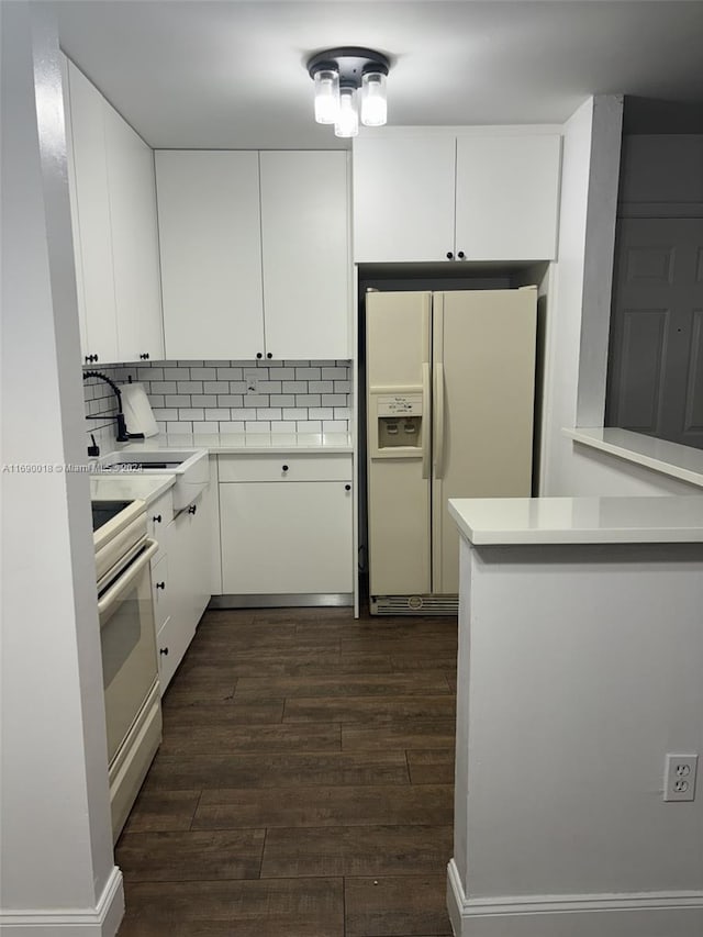 kitchen featuring white cabinetry, kitchen peninsula, dark wood-type flooring, and white appliances