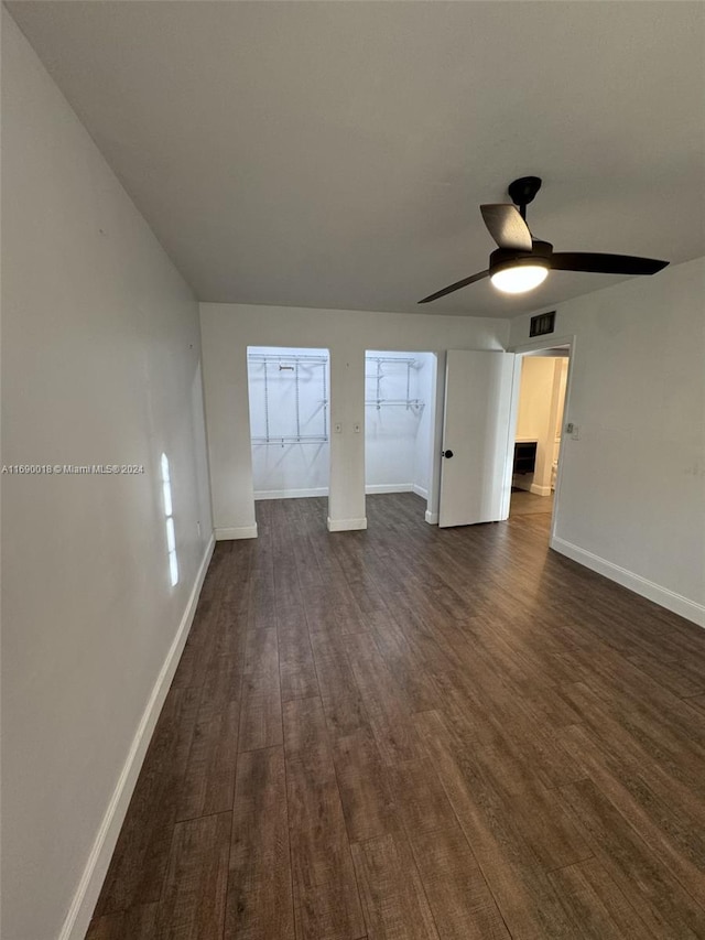 unfurnished living room with dark hardwood / wood-style flooring and ceiling fan