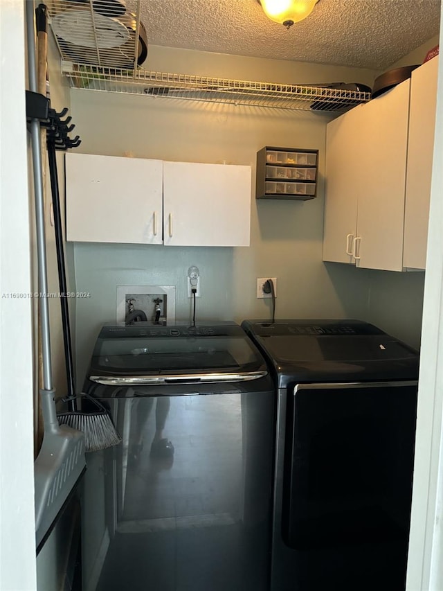 clothes washing area with cabinets, washing machine and dryer, and a textured ceiling