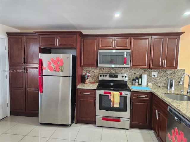 kitchen featuring light stone counters, sink, tasteful backsplash, light tile patterned floors, and appliances with stainless steel finishes