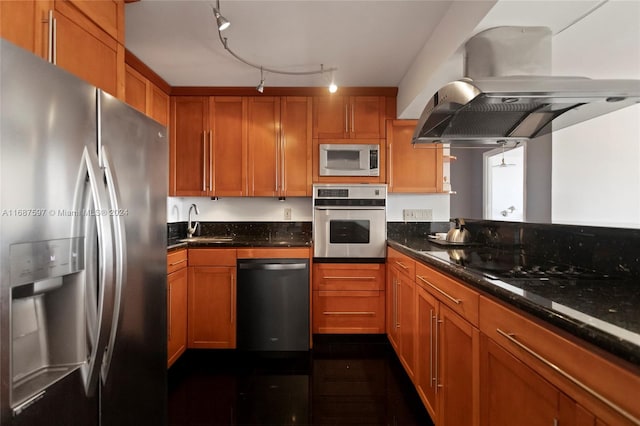 kitchen with dark stone countertops, island range hood, track lighting, and appliances with stainless steel finishes