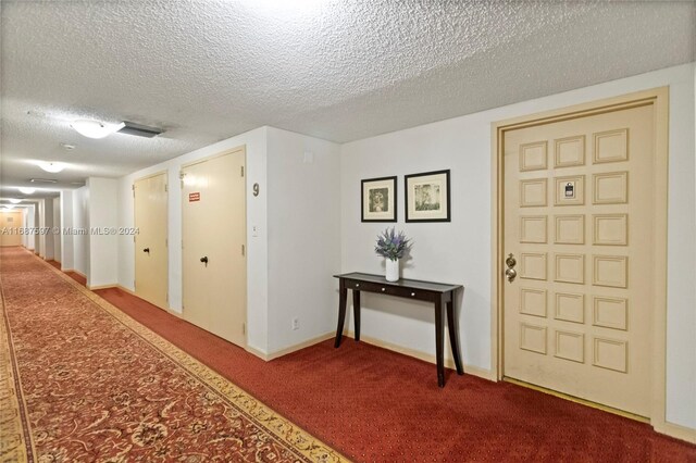 hallway with a textured ceiling and carpet