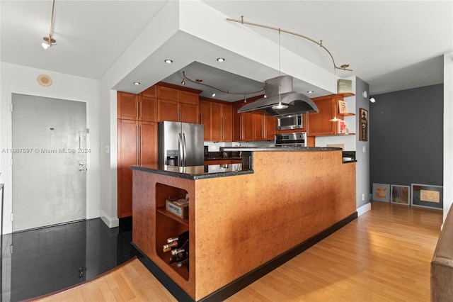 kitchen with stainless steel appliances, kitchen peninsula, decorative light fixtures, light hardwood / wood-style flooring, and island exhaust hood