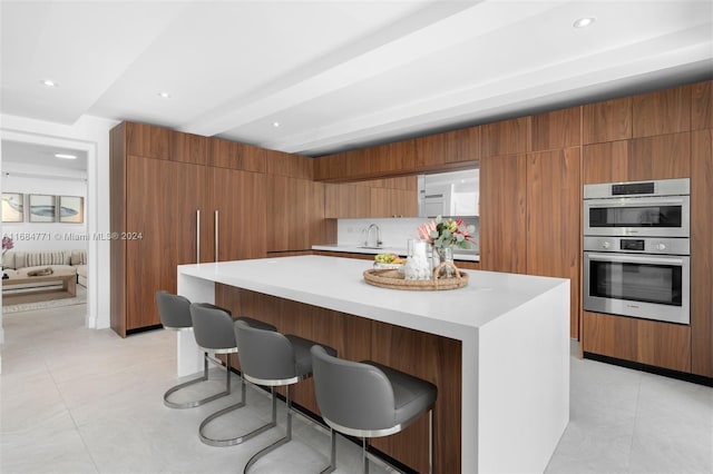 kitchen featuring a breakfast bar area, stainless steel double oven, light tile patterned floors, and a spacious island