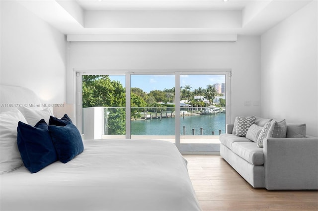 bedroom with access to exterior, a water view, and light hardwood / wood-style floors