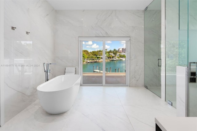 bathroom featuring separate shower and tub, a water view, and tile walls