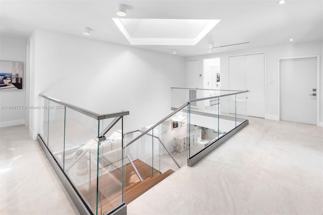 hall with a tray ceiling and a skylight